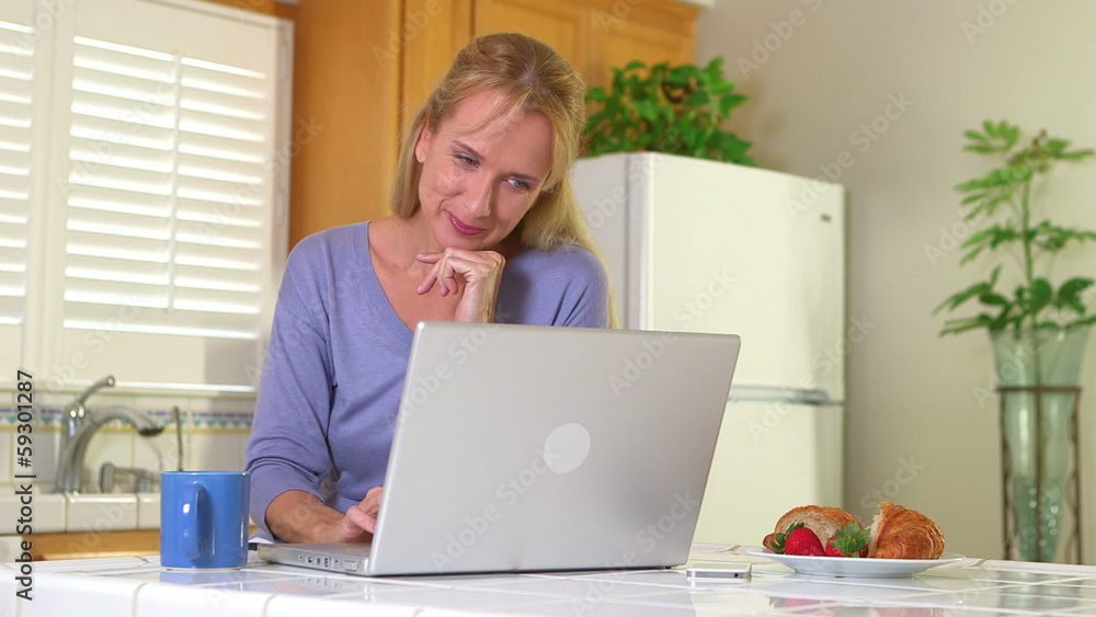 Adult woman drinking morning coffee while using computer Adult woman drinking morning coffee while using computer
