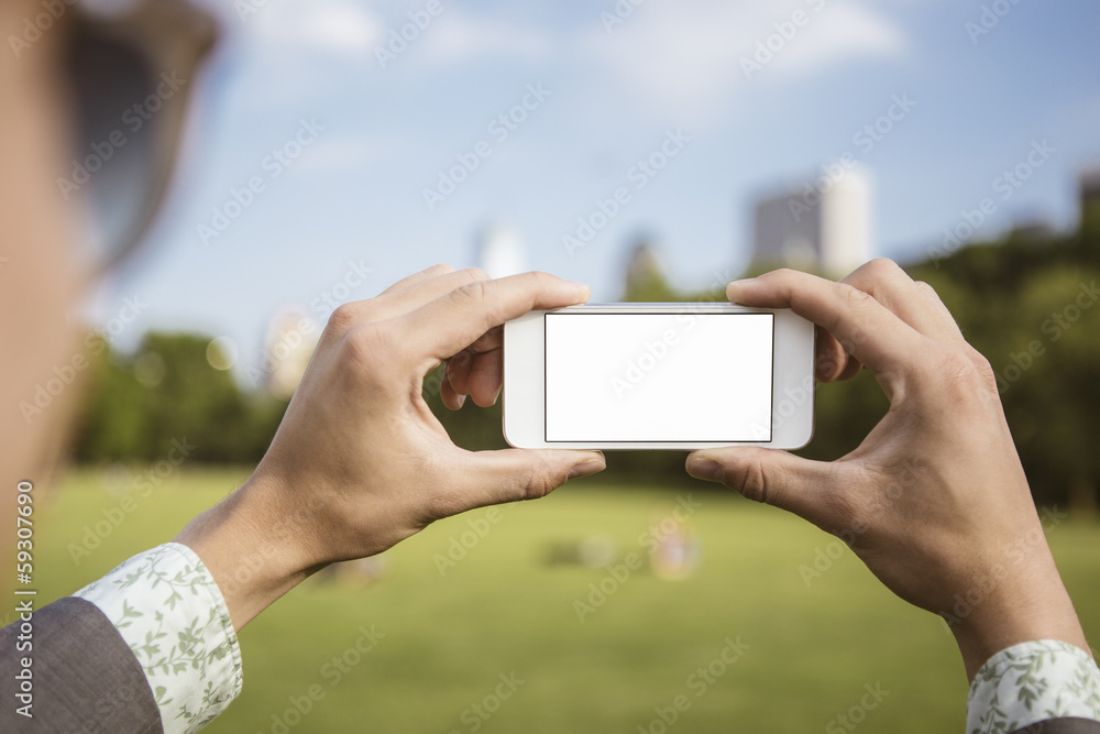 Person holding Smartphone to take a picture in park
