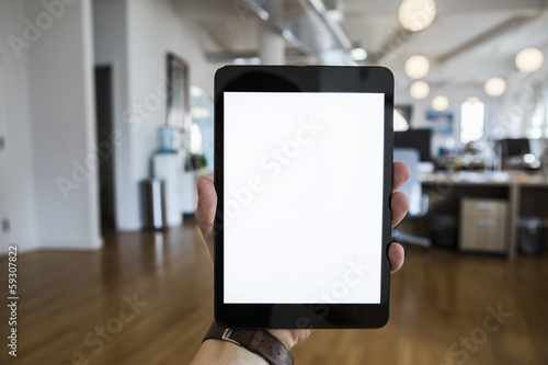 Person in the office holding a touch screen device.