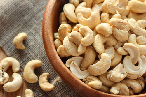 Raw cashews close-up in wooden bowl on sackcloth photo