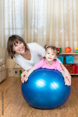 mother and kid play with fitness ball indoors