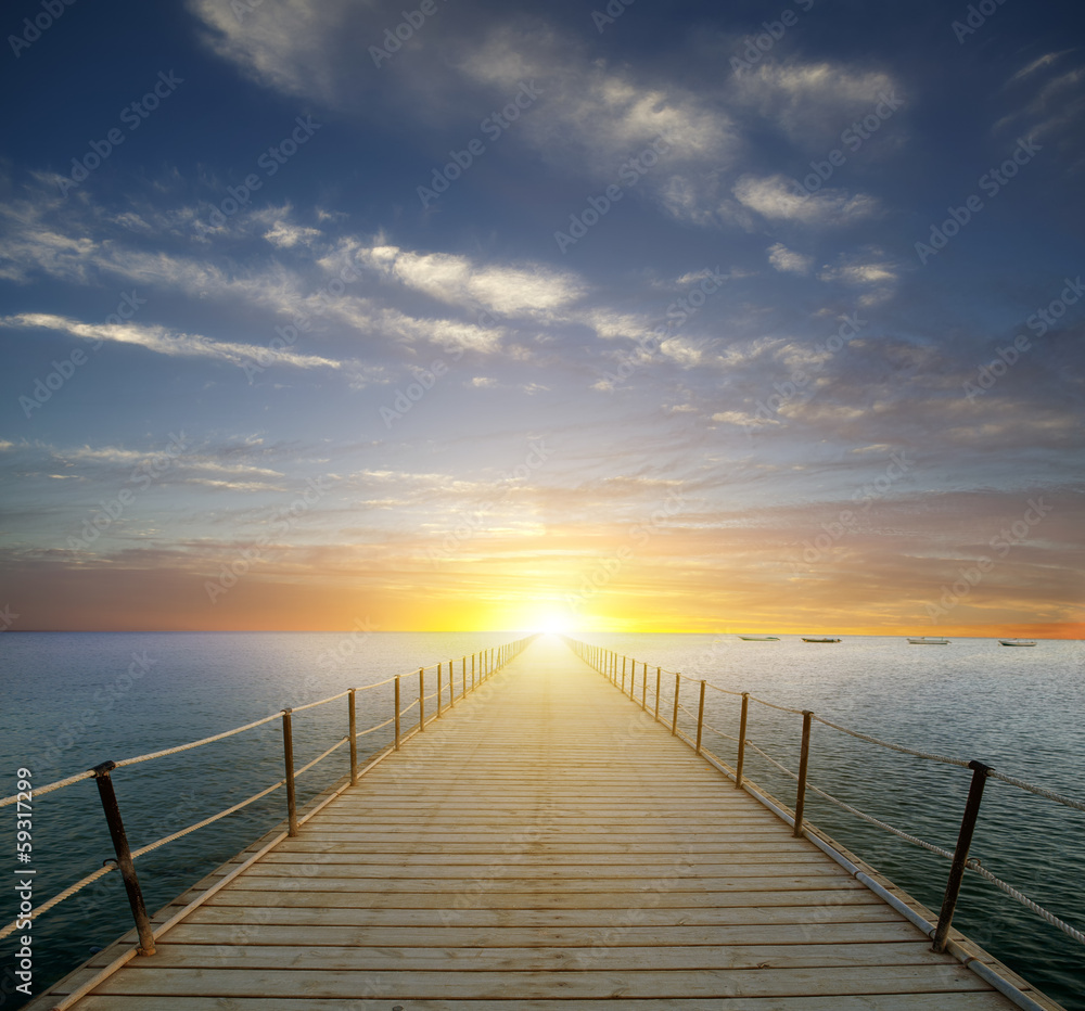 Sunset over the sea. Pier on the foreground