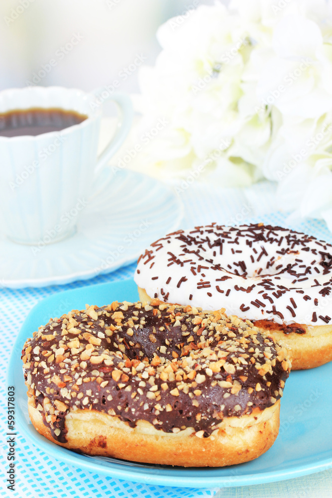 Sweet donuts with cup of tea on table on light background