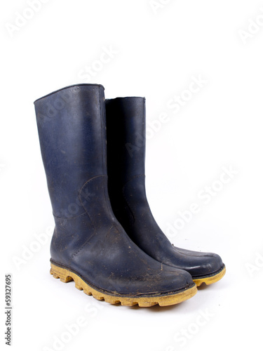 Pair of dark blue dirty rubber boots over a white background
