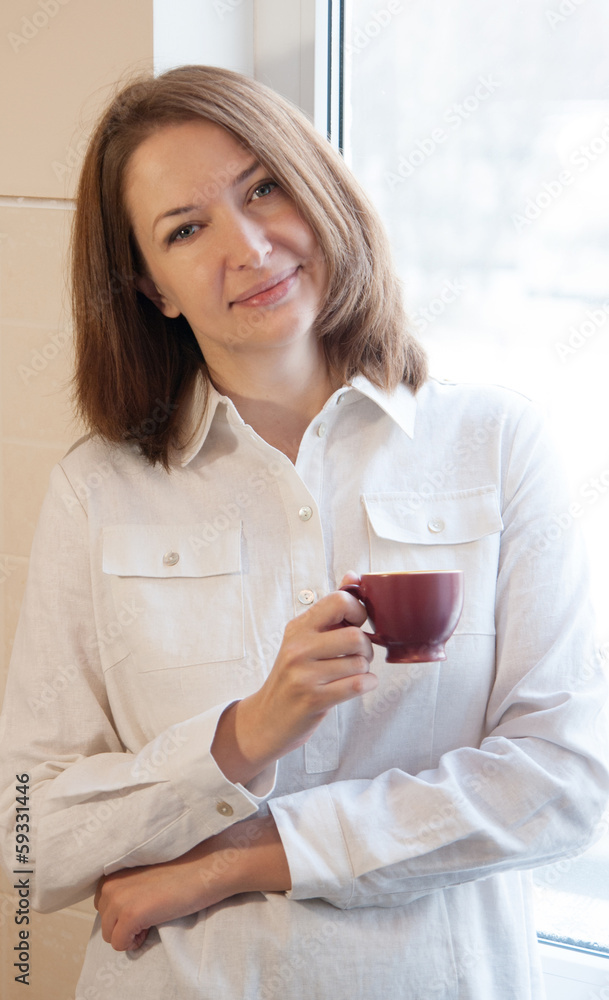 beautiful woman at window with cup of coffee beautiful woman at window with cup of coffee