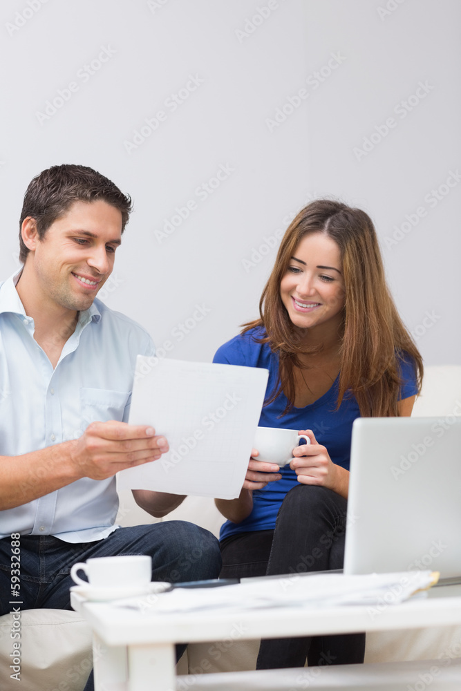 Smiling couple paying their bills online at home Smiling couple paying their bills online at home