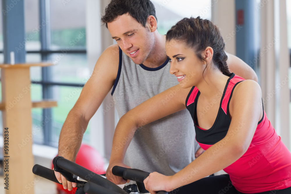 Trainer helping woman work out at spinning class