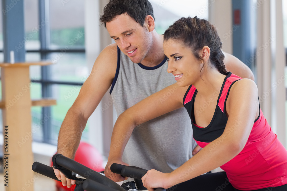 Trainer helping woman work out at spinning class Trainer helping woman work out at spinning class