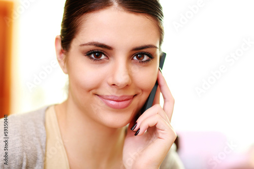 Young happy smiling woman talking on the phone at home