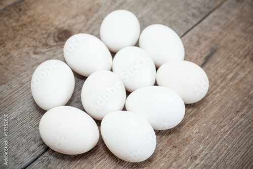 Ten chicken white eggs laying on wooden floor