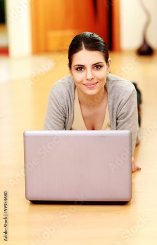 Young beautiful woman lying on the floor with laptop