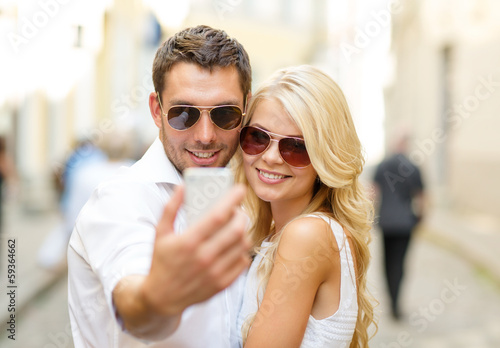 smiling couple with smartphone in the city