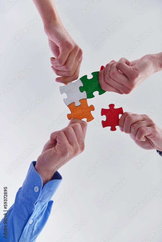 Fototapeta premium Group of business people assembling jigsaw puzzle