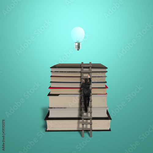 Businessman climbing on stack of books with ladder and bulb photo