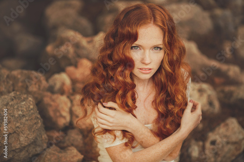 Portrait of young beautiful redhair woman standing in green park photo