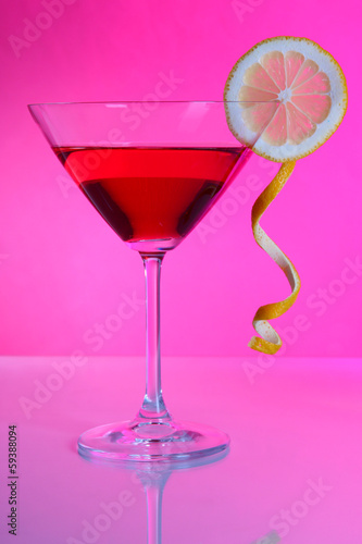 Red cocktail in martini glass on pink background