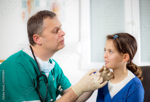 doctor gives a pill to little girl