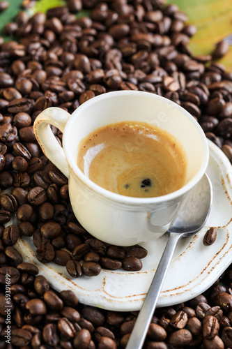 Cup of coffee with a creamy surface and coffee beans
