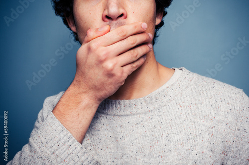 Shocked young man with his hand on his mouth
