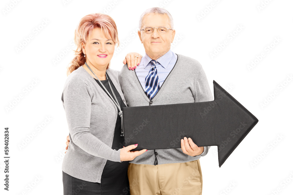 Fototapeta premium Smiling mature man and woman holding a big arrow pointing right