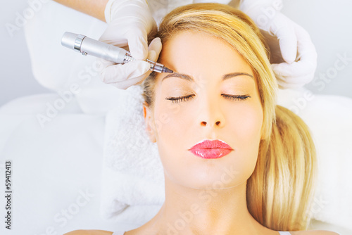 Cosmetologist applying permanent make up on eyebrows
