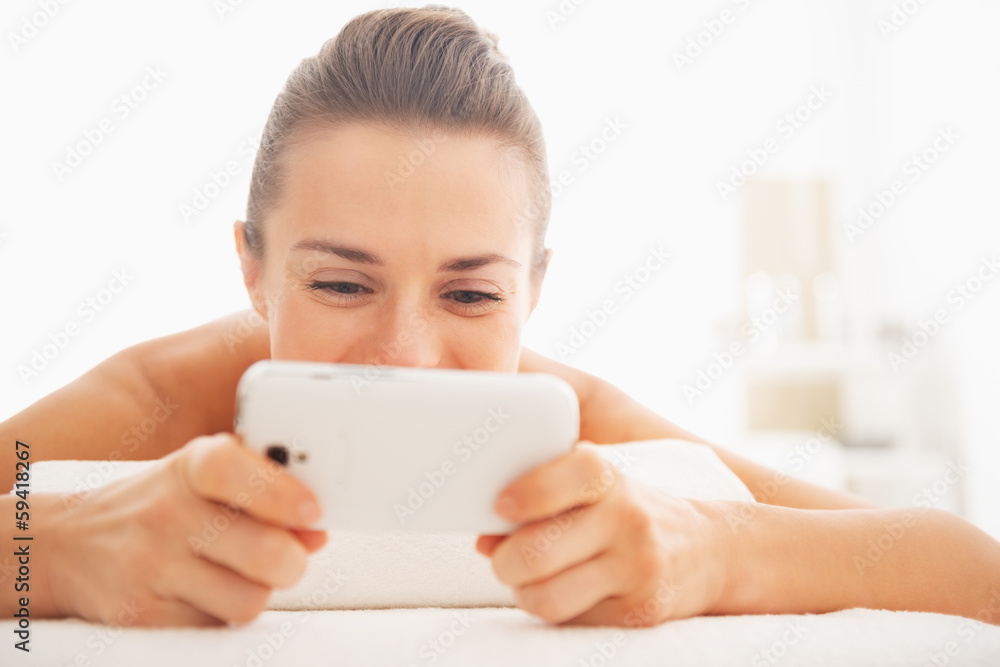 Closeup on young woman writing sms while laying on massage table Closeup on young woman writing sms while laying on massage table