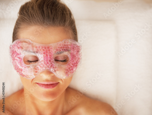 Portrait of young woman in eye mask laying on massage table