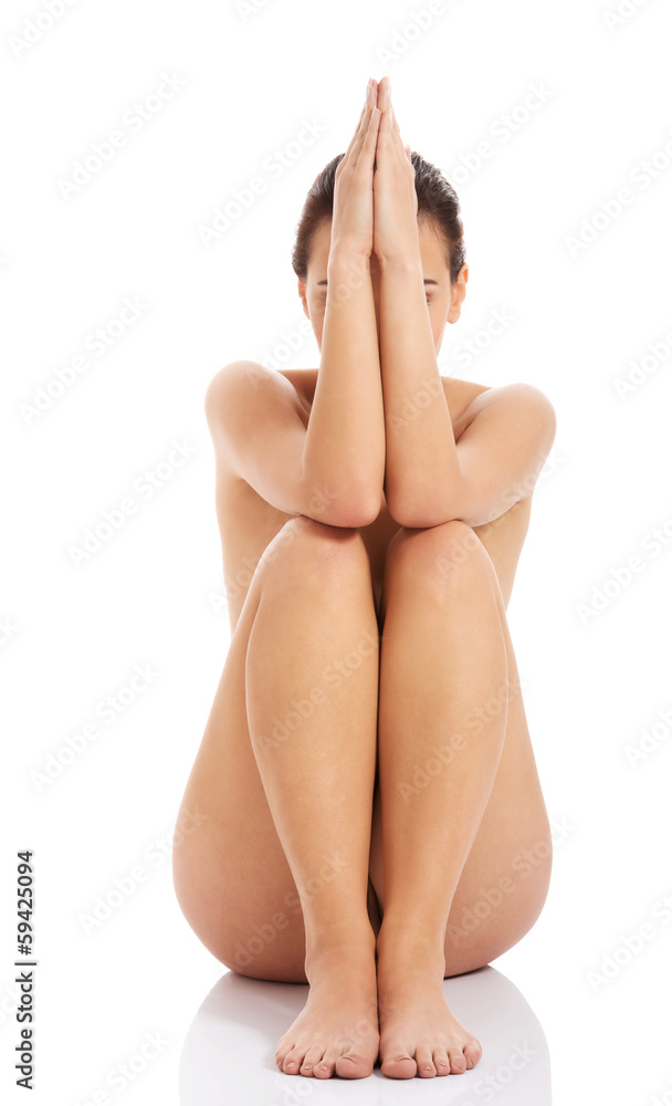 Beautiful naked woman sitting with hands and legs together. Stock Photo |  Adobe Stock