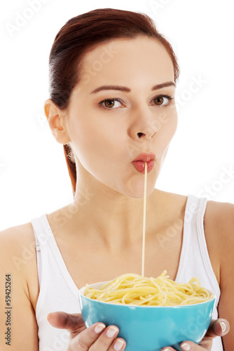 Young beautiful woman eating pasta from a bowl.