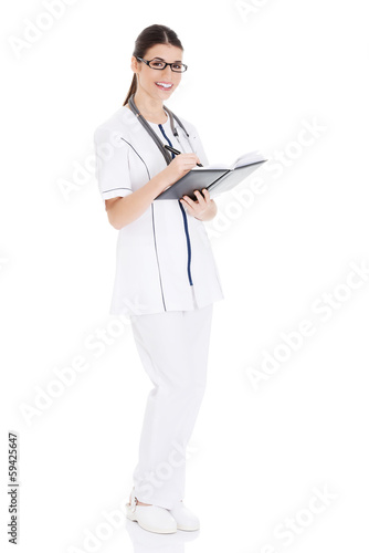 Beautiful young female doctor writing in a workbook.