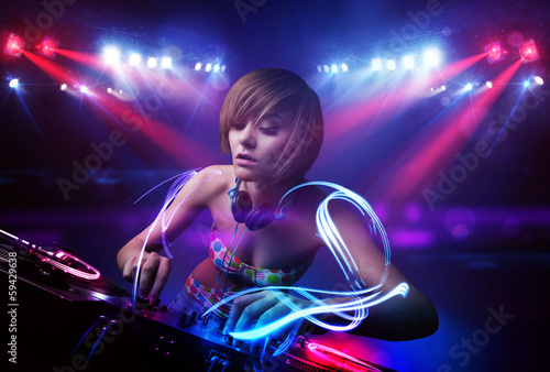 Disc jockey girl playing music with light beam effects on stage © ra2 studio