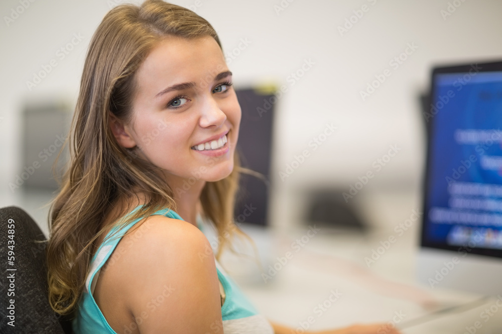Pretty student smiling at camera in the computer room Pretty student smiling at camera in the computer room