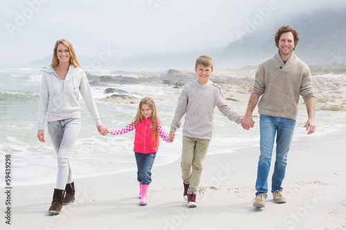 Happy family of four walking hand in hand at beach