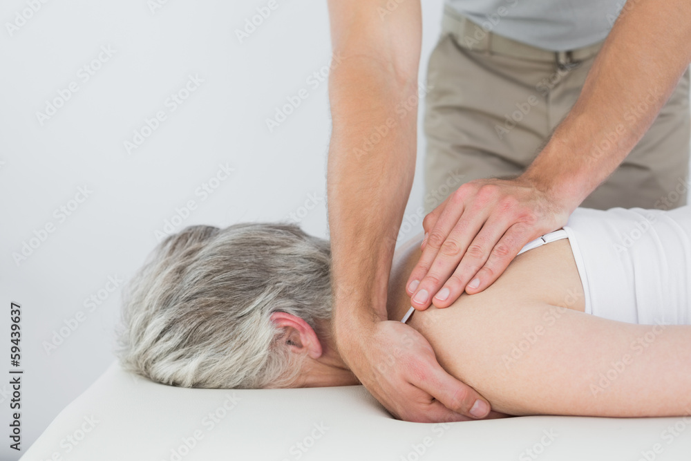 Male physiotherapist massaging a senior woman's shoulder Male physiotherapist massaging a senior woman's shoulder