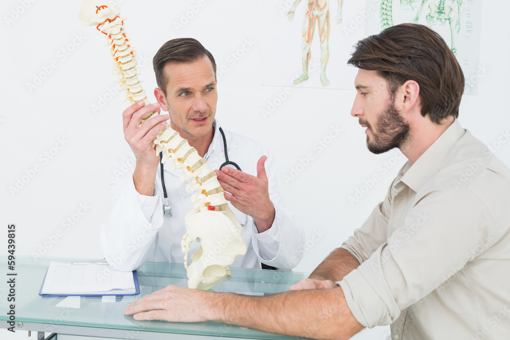 Male doctor explaining the spine to a patient Male doctor explaining the spine to a patient