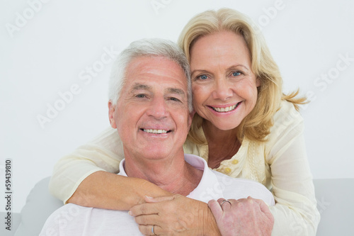 Happy senior woman embracing man from behind