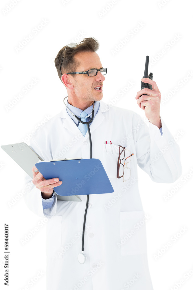 Annoyed doctor with clipboard talking on wireless radio Annoyed doctor with clipboard talking on wireless radio