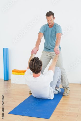 Male therapist assisting man with stretching exercises