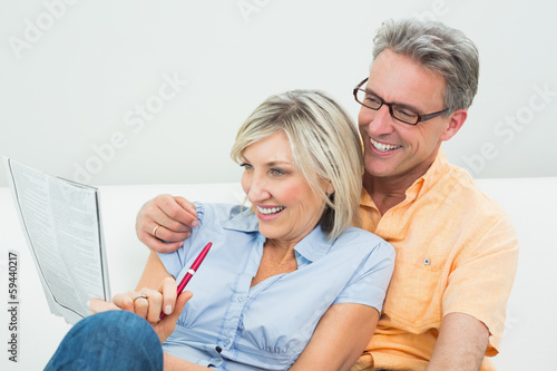 Happy couple doing the newspaper crossword puzzle at home