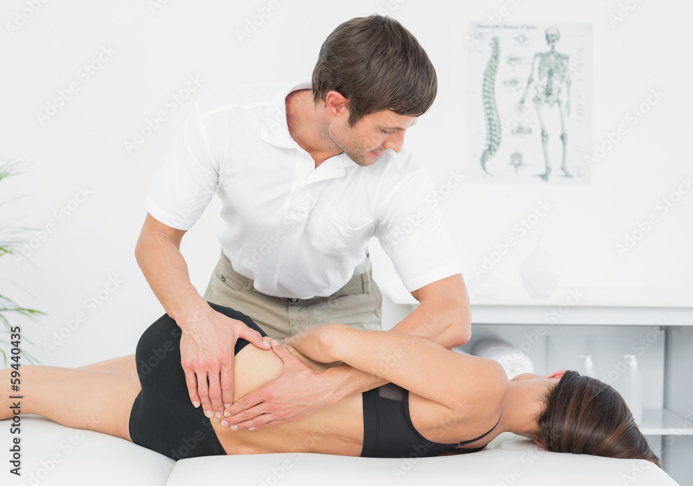 Physiotherapist massaging woman's back in medical office Physiotherapist massaging woman's back in medical office