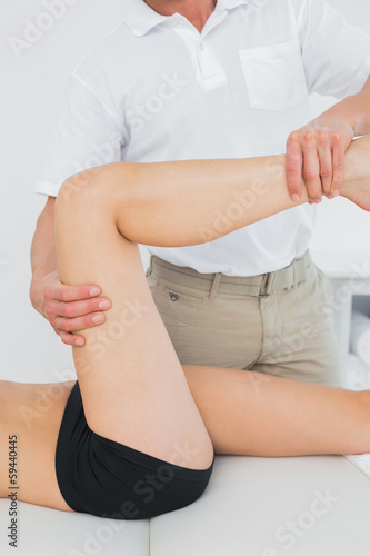 Male physiotherapist examining a young woman s leg