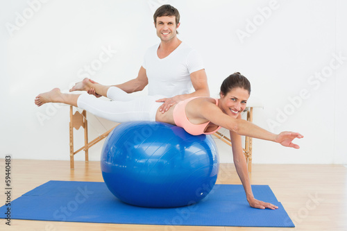 Physical therapist assisting woman with yoga ball