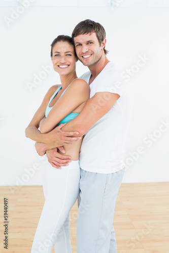 Fit couple embracing in fitness studio