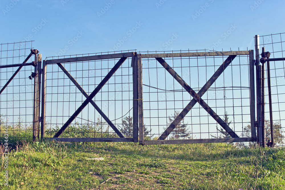 Old wooden metal fence and green grass with blue sky