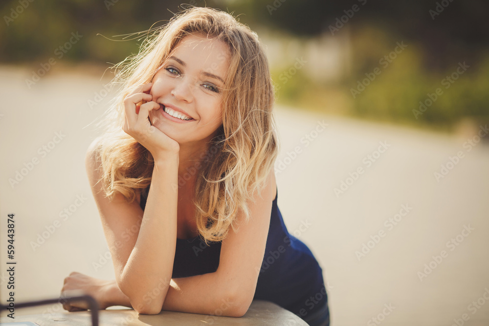 Naklejka premium Portrait of a young beautiful smiling blonde woman outdoors