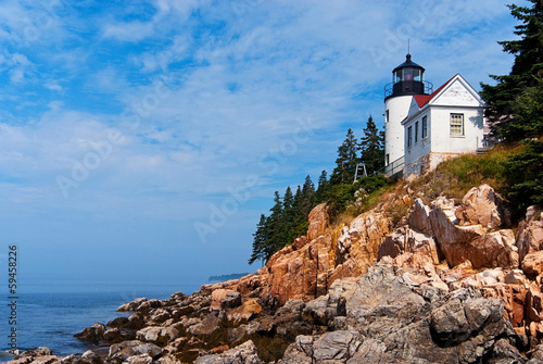 Bass Harbor lighthouse sits above jagged rocky cliffs in Acadia National Park during low tide in Maine. It is a favorite summertime New England tourist attraction.