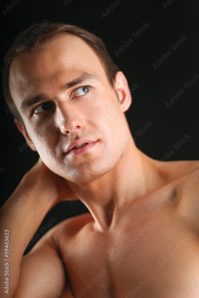 Portrait of a naked muscular man, isolated on black background.