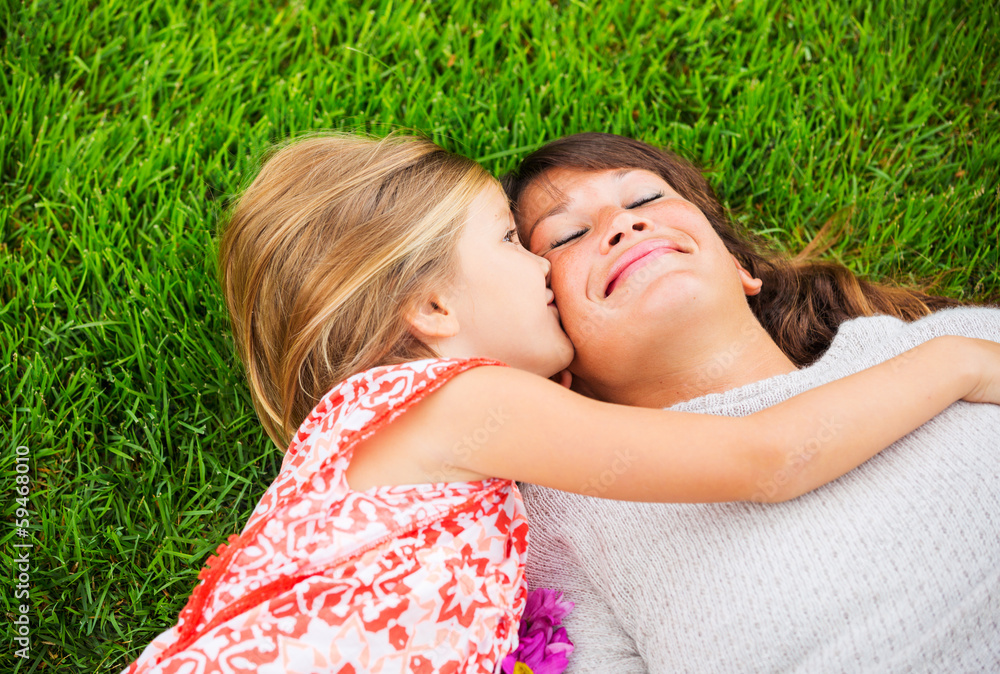 Happy mother and daughter relaxing outside on green grass. Spend Happy mother and daughter relaxing outside on green grass. Spend