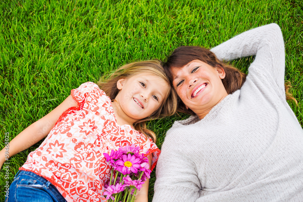 Happy mother and daughter relaxing outside on green grass. Spend Happy mother and daughter relaxing outside on green grass. Spend