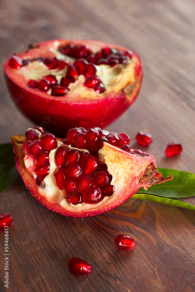 Fresh ripe pomegranate with leaves on a wooden board.